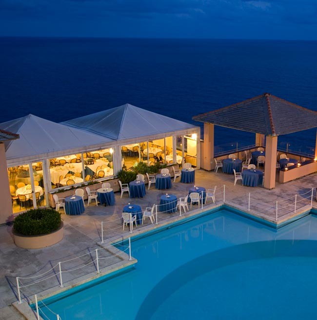 Nachtfoto des runden Swimmingpools mit Blick auf das Meer im Hotel Punta San Martino