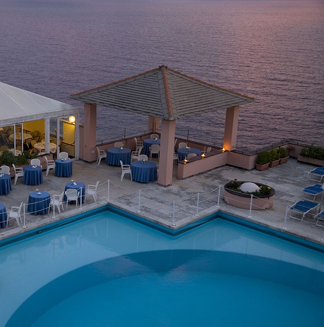 Photo du soir de la piscine ronde surplombant la mer de l'hôtel Punta San Martino