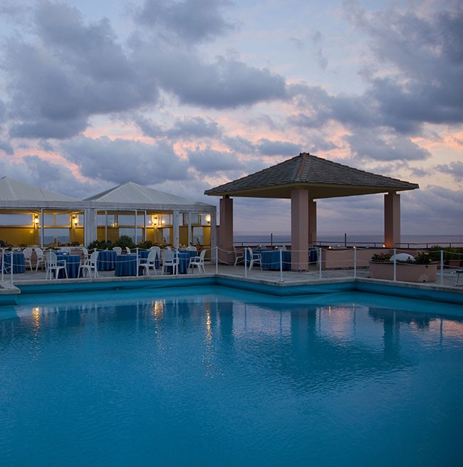 Foto serale della piscina tonda affacciata sul mare dell'Hotel Punta San Martino